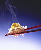 Steaming rice with butter curl on red chopsticks