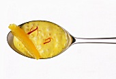 Saffron orange sauce with orange segment on spoon