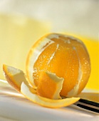 Orange, halb geschält, mit Messer