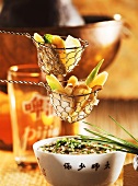 Spring fondue with shiitake mushrooms in sieve above bowl