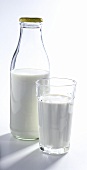Milch in halb gefüllter Flasche und im Glas