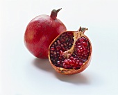 Half a pomegranate with seeds in front of whole pomegranate