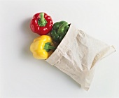 Three peppers (red, yellow, green) in paper bag