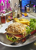 Cheeseburger with ham, bacon etc on tray with cutlery