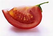 A wedge of tomato with stalk on white background