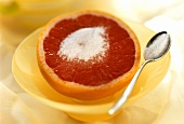 Half a pink grapefruit, sweetened, spoon with sugar
