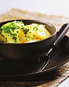 Potato salad sprinkled with chives in black bowl