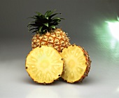 Two pineapple halves in front of a pineapple