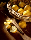 Lemons in a Basket with Sliced Lemons on Wood