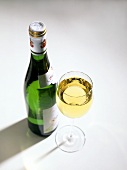 Weissweinflasche und daneben ein Glas Weißwein