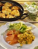 Scrambled egg with salmon on white plate and behind in pan