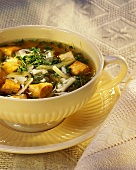 Zwiebelsuppe mit Tofuwürfeln und Kresse in Suppentasse