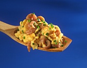 Scrambled egg with shrimps and chives on wooden spoon