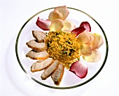 Chicken breast with rice and rose petals on glass plate