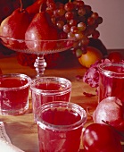 Red jam in jars in front of a fruit bowl