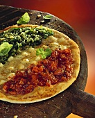 Pizza with tomatoes, spinach & cheese on large wooden paddle