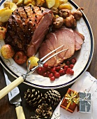 Glazed ham on a platter with cranberries, apples etc