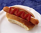 A hot dog with ketchup on a white plate