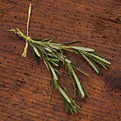A bunch of rosemary with drops of water on wooden background