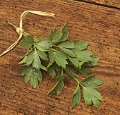 A bunch of lovage with drops of water on wooden background