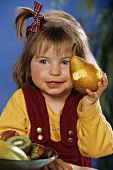 Small girl with pear, with bite taken, in her hand