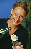 Young blond woman with glass and bottle of mineral water