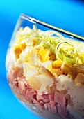Layered salad with ham, eggs, celery, pineapple in dish