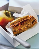 Wholemeal sandwich and apple with knife in a box