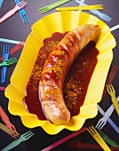 Curry sausage with ketchup in a cardboard dish; Party forks