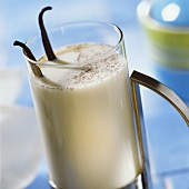 Honey & vanilla flavoured milk in glass with vanilla sticks