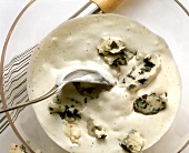 Salad dressing with blue cheese in glass dish with spoon