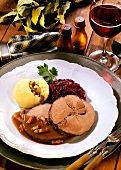 Roast wild boar with dumpling, red cabbage and red wine glass