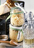 Grated horseradish in two preserving jars; vinegar carafe