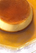 Crème caramel in caramel sauce on a glass plate with icing sugar