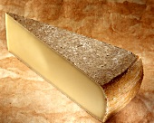 Comte, a French hard cheese, on a brown background