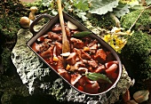 Game with marinade of vegetables & red wine in roasting dish