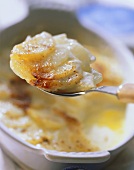 A spoonful of potato gratin over the baking dish