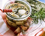 Pickled garlic in pickling jar; sprig of rosemary