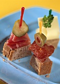 Wheat bread, sausage, olive and gherkin on cocktail sticks