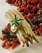 White asparagus with mayonnaise on spoon above strawberries