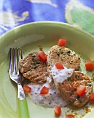 Curried veal fillet with tomato yoghurt on green plate