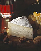 A piece of soft cheese with nuts and grapes