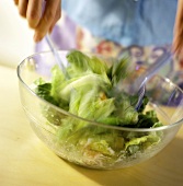 Cäsarsalat in Salatschüssel vermischen