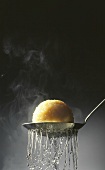 Steaming potato dumpling on a straining spoon