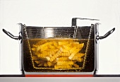 Pommes frites in einem Topf mit heißem Öl fritieren