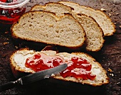 Brotscheiben, eine davon mit Butter und Marmelade bestrichen