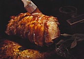 Brushing a rolled pork joint with oil