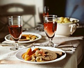 Roast beef with carrots and onions on a plate; Red wine