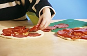 Pizza mit Tomatenscheiben belegen