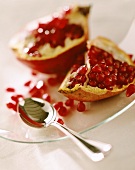 Halved pomegranate on glass plate with spoon